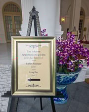 Schild mit Eventhinweis vor Vase mit Orchideen in Haus im Kolonialstil