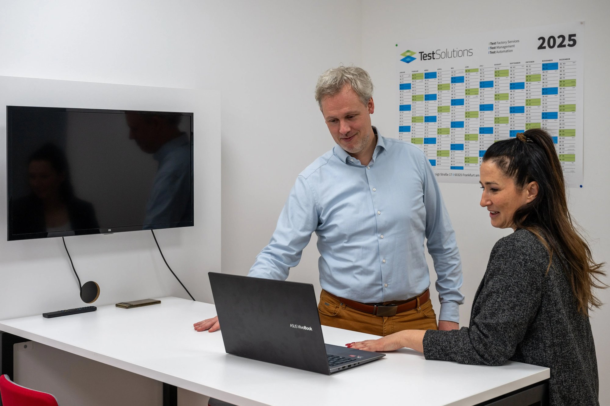 Two people discussing something on a laptop in an office