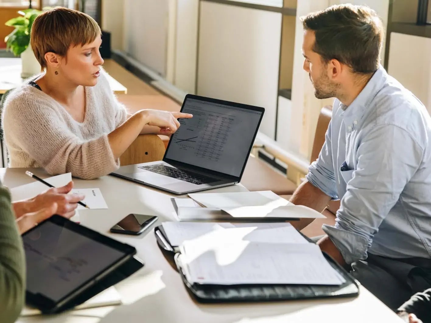 Weibliche Führungskraft zeigt im Team Mobility Daten über Laptop