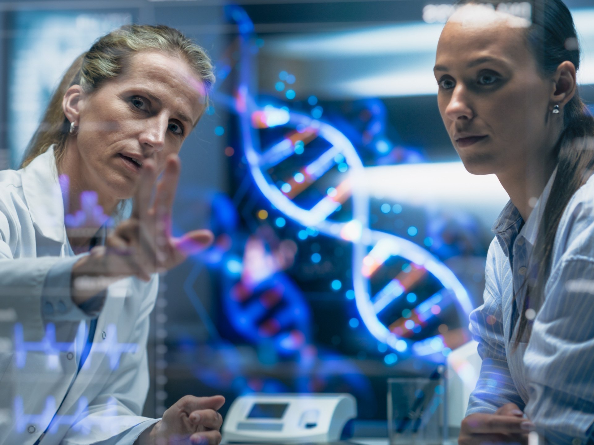 Zwei Frauen in Besprechung vor einem digitalen DNA-Strang