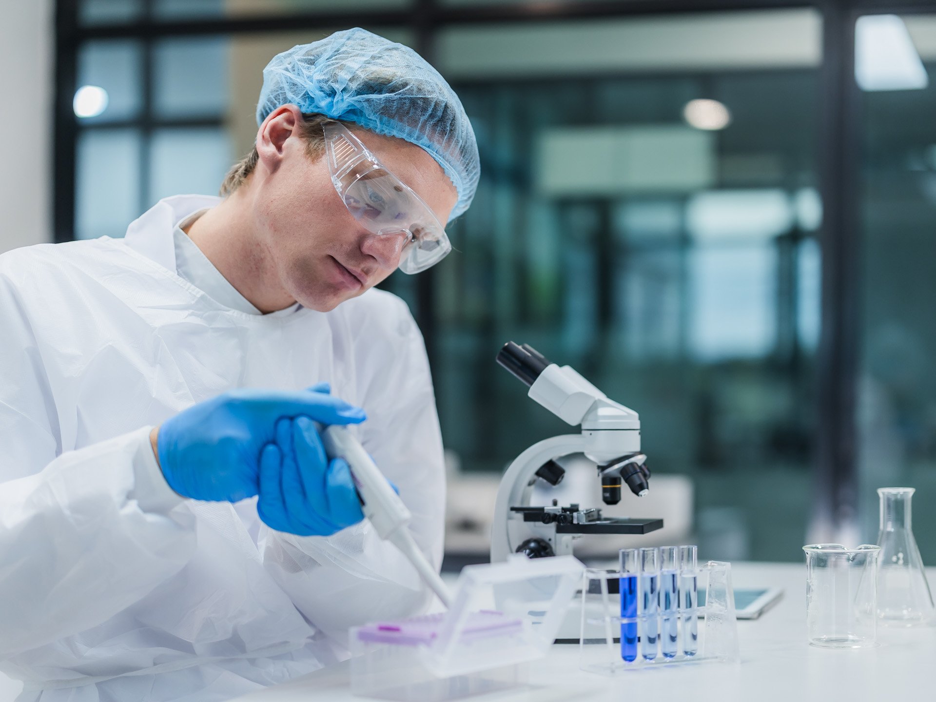 Labormitarbeiter mit Pipette vor Mikroskop